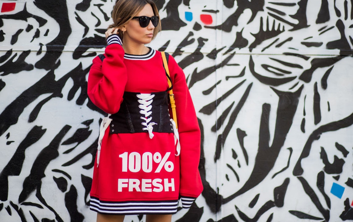 a woman in red in front of a wall with a mural on it